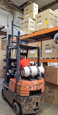 Forklift stacking Mitubishi HVAC unit boxes in warehouse
